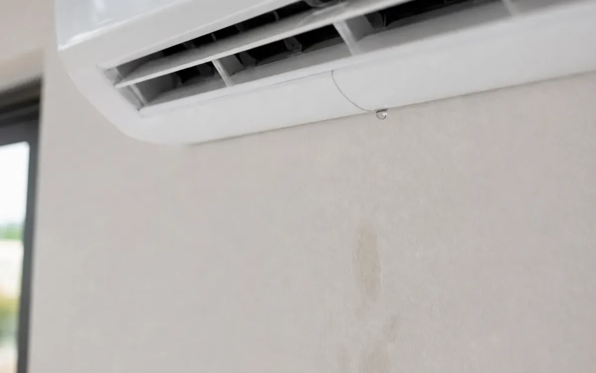 Kapljica vode na spodnjem robu notranje enote klimatske naprave in vlažna sled na steni