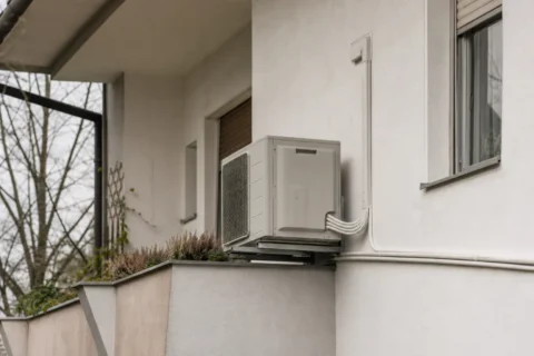 Zunanja enota multi split sistema na balkonu z več cevnimi povezavami ob steni